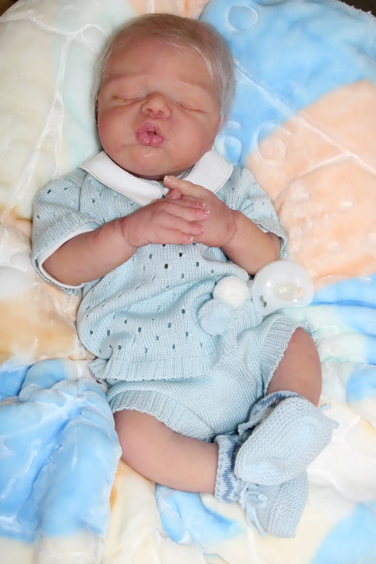 Bébé reborn en silicone allongé sur le dos avec une tunique. Modèle Charlotte.